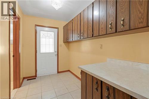 MUDROOM with SIDE DOOR ENTRANCE TO PATIO: Built-in wood-finish cabinetry with decorative hardware, light-toned countertop, and tiled flooring - 2535 Privet Crescent, Mississauga, ON - Indoor Photo Showing Other Room