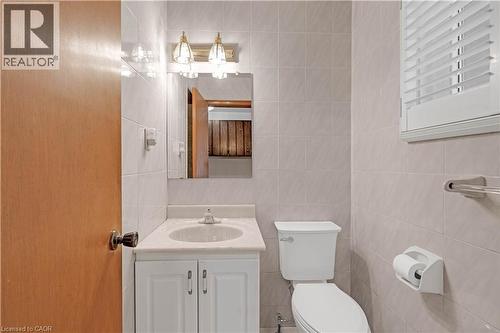 Bathroom featuring a white vanity with integrated sink, a wall-mounted mirror, and tiled walls - 2535 Privet Crescent, Mississauga, ON - Indoor Photo Showing Bathroom