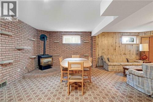 Brick accent wall with integrated shelving, wood-burning stove on a raised hearth, wood-paneled wall, and multiple windows - 2535 Privet Crescent, Mississauga, ON - Indoor Photo Showing Other Room