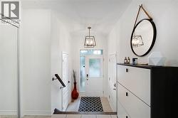Entryway featuring tile flooring, a frosted glass front door with a transom window, a built-in closet with mirrored sliding doors, and a contemporary ceiling light fixture - 