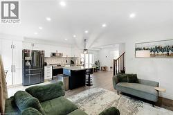 White cabinetry, stainless steel appliances, marble-patterned backsplash, recessed lighting, and wood-finish flooring - 