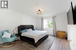 Spacious room featuring wood-finish flooring, a contemporary ceiling fixture, and ample natural light from a large window - 