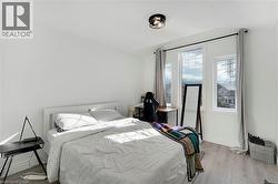 Bright interior space with multiple windows, wood-finish flooring, white walls, and a contemporary flush-mount ceiling light fixture - 