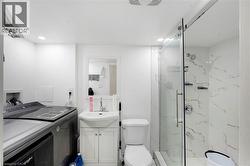 Full bathroom featuring a shower with a clear glass enclosure, white and gold-toned veined tile, recessed lighting, a pedestal sink with vanity, and a toilet - 