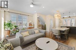 Open-concept living space featuring wood-finish flooring, recessed lighting, a modern ceiling fan, and a dining area with a contemporary chandelier - 