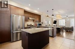 Kitchen featuring stainless steel appliances, wood-finish cabinetry, a central island with a light-toned countertop, and recessed lighting - 