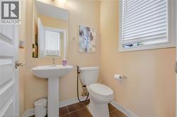 Pedestal sink with chrome faucet, toilet, wall-mounted mirror, and a window with blinds - 