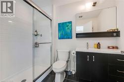 Glass-enclosed shower with white subway tile, dark-finish vanity with countertop, wall-mounted mirror with integrated shelf, and dark-finish floor tiles - 