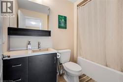 Full bathroom featuring a dark wood-finish vanity with an integrated sink, a built-in mirror, and a white bathtub - 