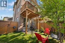 Brick exterior featuring a wood balcony, sliding glass door, and fenced yard with grass - 