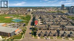 Urban setting featuring a residential street, townhome developments, a baseball diamond, tennis courts, and the ocean horizon - 