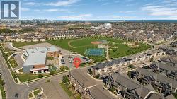 Aerial perspective displaying a neighborhood with various residential structures, a large green space featuring a baseball diamond and tennis courts, and a prominent institutional building - 