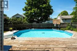 Backyard featuring a built-in swimming pool with a surrounding wood-finish deck - 