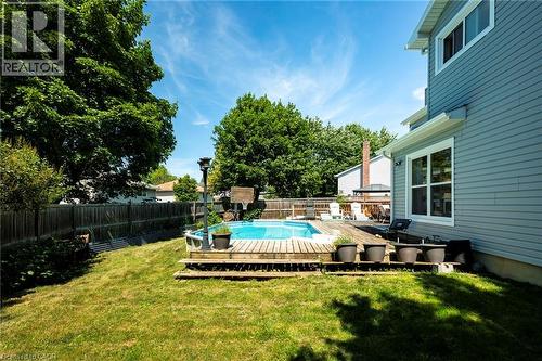 Expansive backyard featuring a manicured lawn, a swimming pool with a surrounding wood deck, and a privacy fence - 364 Stoneheight Place, Waterloo, ON 