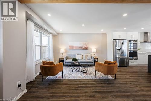 Open-concept living area with dark wood-finish flooring, recessed lighting, and a visible kitchen featuring white cabinetry and stainless steel appliances - 364 Stoneheight Place, Waterloo, ON 