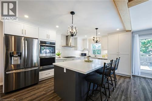 Stainless steel appliances, white cabinetry with crown molding, recessed lighting, wood-finish flooring, and a central island with a solid surface countertop - 364 Stoneheight Place, Waterloo, ON 