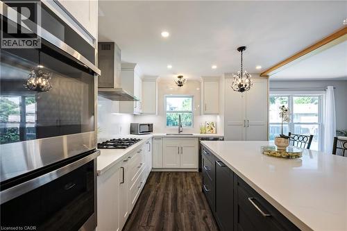 Gourmet kitchen featuring stainless steel appliances, wood-finish flooring, white cabinetry, a central island with white countertops, and recessed lighting - 364 Stoneheight Place, Waterloo, ON 