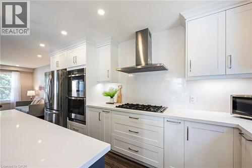 White cabinetry with dark hardware, stainless steel appliances, stainless steel range hood, built-in gas cooktop, and light-toned countertops - 364 Stoneheight Place, Waterloo, ON 