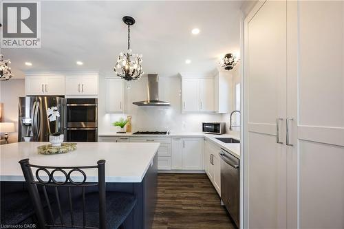 Kitchen featuring a central island with white countertop, stainless steel appliances, dark wood-finish flooring, white cabinetry, and recessed lighting - 364 Stoneheight Place, Waterloo, ON 