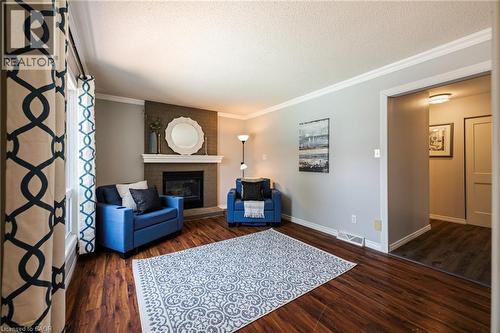 Wood-finish flooring, corner fireplace with white mantle, crown molding, and a visible doorway - 364 Stoneheight Place, Waterloo, ON 