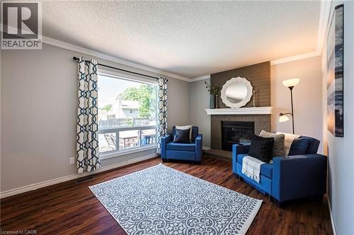 Wood-finish flooring, a prominent window, a fireplace with a brick surround, a white mantel, and crown molding - 364 Stoneheight Place, Waterloo, ON 