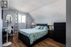 Wood-finish flooring with a window offering natural light, textured ceiling, and painted walls - 