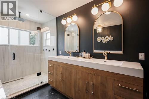 Dual-sink vanity with wood-finish cabinetry, gold-tone fixtures, and arched mirrors - 364 Stoneheight Place, Waterloo, ON 