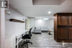 Recessed lighting, wood-finish flooring, white walls, and a built-in wood-paneled feature - 