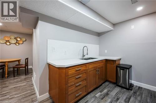 Compact wet bar with a dual-basin stainless steel sink, light-toned countertop, and wood-finish cabinetry - 364 Stoneheight Place, Waterloo, ON 