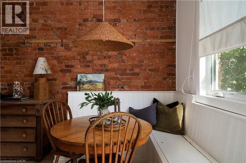 Exposed brick wall, built-in window seating, wood-finish flooring, white paneled wainscoting, and a single pane window - 29 Steven Street, Hamilton, ON 