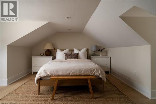 Sloped ceiling architecture with recessed lighting, light wood-finish flooring, and white built-in nightstands - 29 Steven Street, Hamilton, ON 