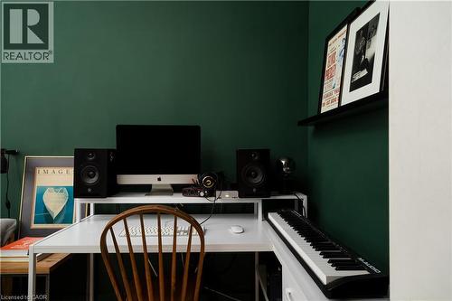 Corner workspace featuring a white desk, dark green accent wall, and a black floating shelf - 29 Steven Street, Hamilton, ON 
