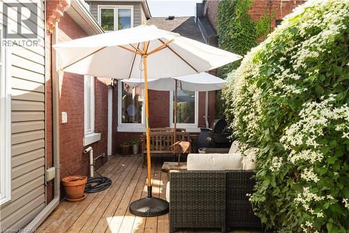 Wood deck outdoor space featuring a red brick exterior, horizontal siding, and lush flowering greenery - 29 Steven Street, Hamilton, ON 