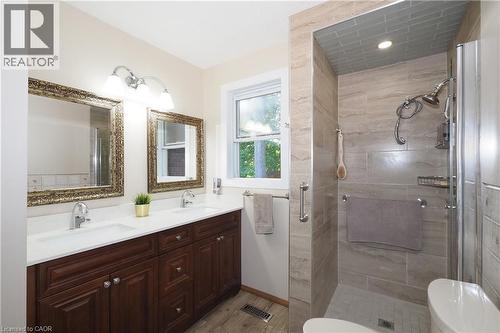Double vanity with white countertops, wood-finish cabinetry, and framed mirrors - 185 Southwood Drive, Kitchener, ON 