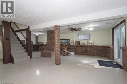 Spacious lower level featuring a brick accent wall, a ceiling fan, and a light-colored flooring - 185 Southwood Drive, Kitchener, ON 