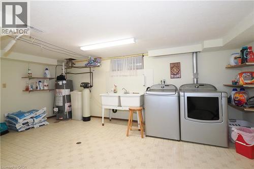 Utility room featuring a double basin sink, water heater, water softener, and built-in shelving - 185 Southwood Drive, Kitchener, ON 