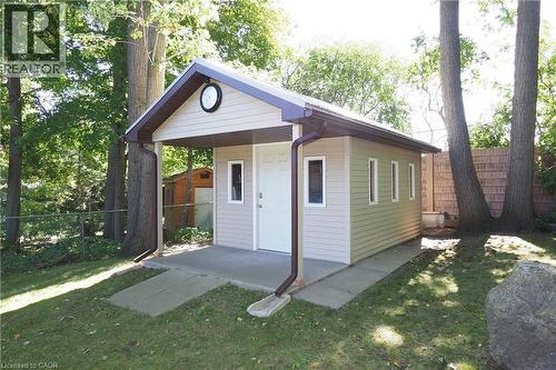 Detached auxiliary structure featuring neutral siding, a covered entry, multiple windows, and a concrete patio - 185 Southwood Drive, Kitchener, ON 