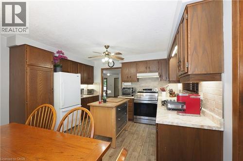 Kitchen featuring wood-finish cabinetry, stone-finish countertops, stainless steel range, and tile backsplash - 185 Southwood Drive, Kitchener, ON 