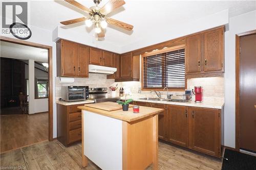 Kitchen featuring wood-finish cabinetry, tile backsplash, laminate countertops, and wood-finish flooring - 185 Southwood Drive, Kitchener, ON 