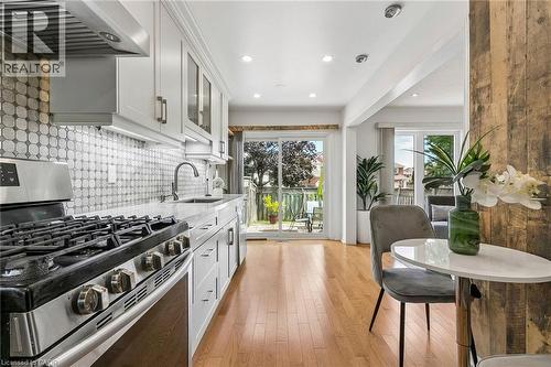 Contemporary kitchen featuring light wood-finish flooring, white cabinetry, integrated stainless-steel appliances, a mosaic tile backsplash, and recessed lighting - 1373 Quest Circle, Mississauga, ON 