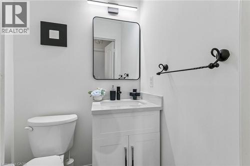 White vanity with a white countertop and integrated sink, black single-handle faucet, and a rectangular mirror with a black frame - 1373 Quest Circle, Mississauga, ON 