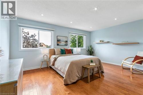 Wood-finish flooring, recessed ceiling lighting, two windows with white frames, light blue wall color, and two floating wood shelves - 1373 Quest Circle, Mississauga, ON 