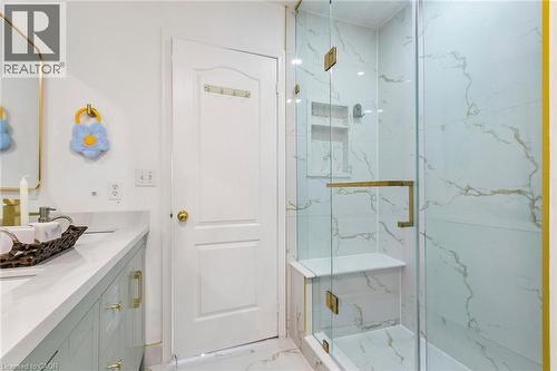 Glass-enclosed shower with a built-in bench, recessed shelf, and gold-finish hardware - 1373 Quest Circle, Mississauga, ON 