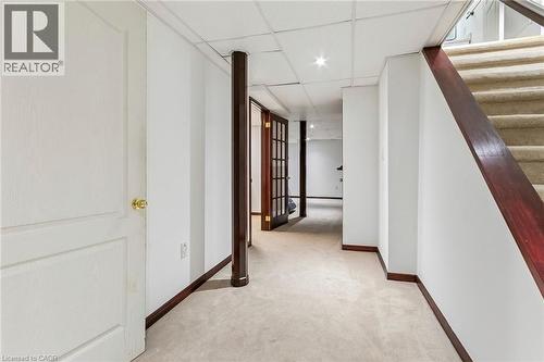 Carpeted flooring extending through a hallway with a drop ceiling, recessed lighting, and a white paneled door - 1373 Quest Circle, Mississauga, ON 