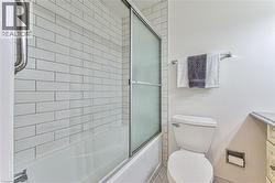 Main floor 4 pc bathroom with subway tiled tub to ceiling with glass doors. - 