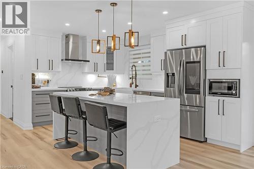 Kitchen featuring a large center island, stainless steel appliances, a range hood, pendant lighting, and wood-finish flooring - 4236 Longmoor Drive, Burlington, ON 
