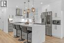 Kitchen featuring a large center island, stainless steel appliances, a range hood, pendant lighting, and wood-finish flooring - 4236 Longmoor Drive, Burlington, ON 