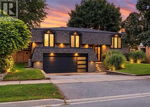 Contemporary architecture featuring a dark shingle roof, integrated garage, and stone-clad entryway - 4236 Longmoor Drive, Burlington, ON 