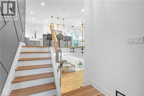 Staircase with wood-finish treads, white risers, and a glass railing with a wood-finish top rail - 4236 Longmoor Drive, Burlington, ON 