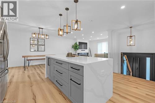 Expansive kitchen island with a waterfall countertop, gray cabinetry, and matte black hardware - 4236 Longmoor Drive, Burlington, ON 
